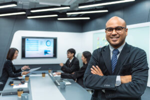 A man in a suit stands confidently before a conference table, representing an outsourced chief investment officer.